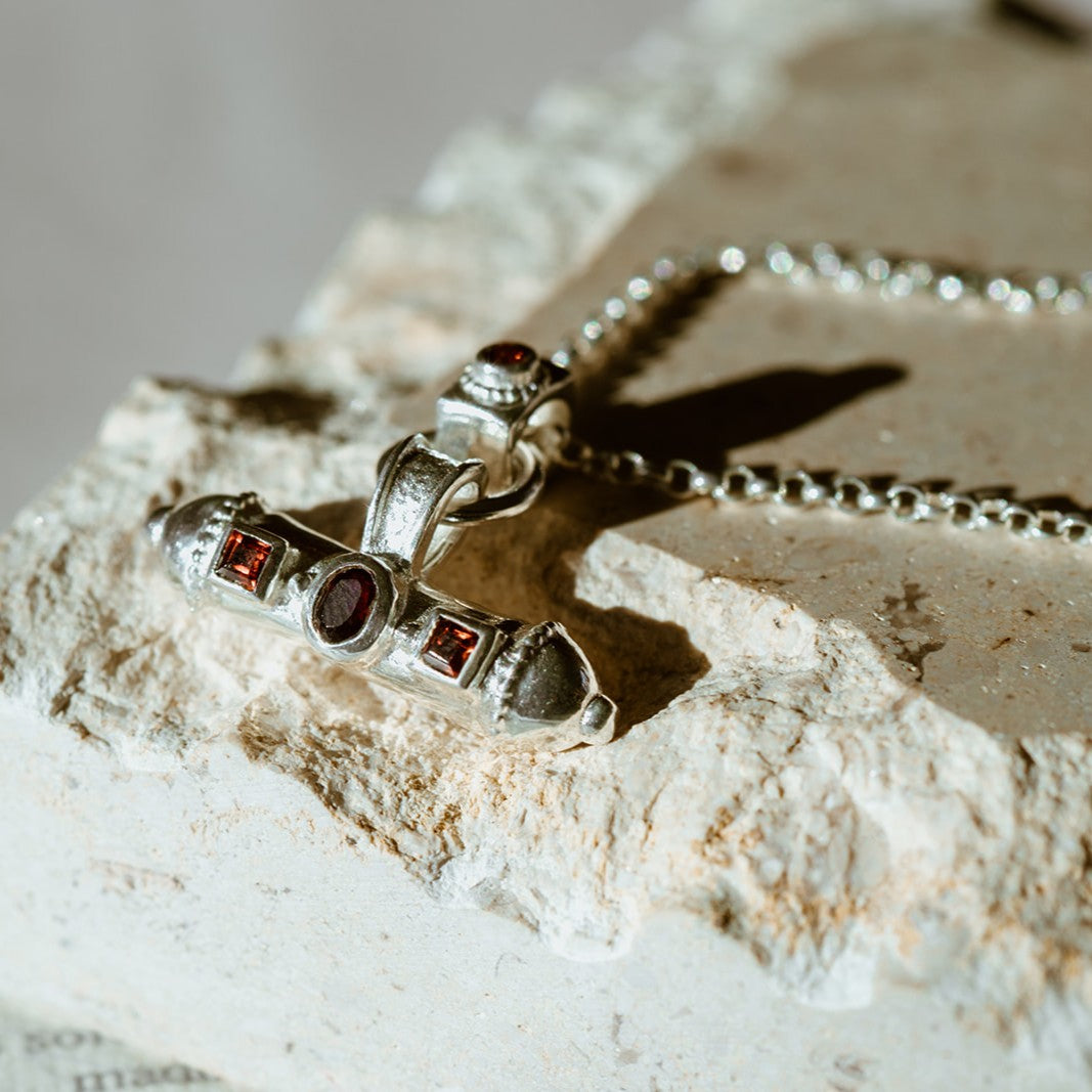 Detailed view of the Nivara Amulet’s hand-crafted surface and red garnet gemston