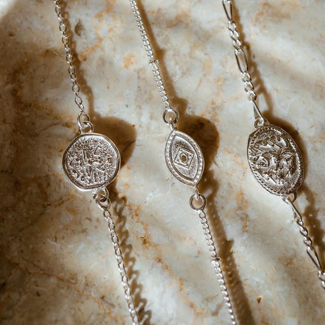 Sterling silver stacking bracelets with dainty chain, featuring an evil eye, small Lakshmi and delicate Durga charms