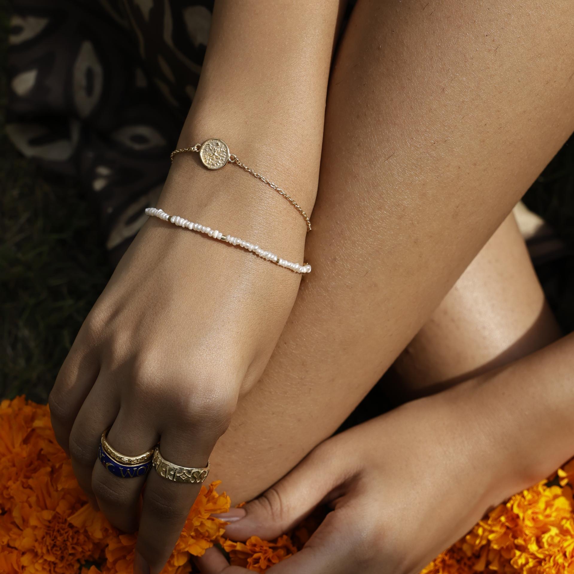 Close up of hands wearing Baby Lakshmi gold vermeil stacking bracelet, Arambol pearl bracelet and rings by Loft & Daughter