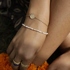 Close up of wrist wearing Baby Lakshmi stacking bracelet with delicate pearl bracelet by Loft & Daughter