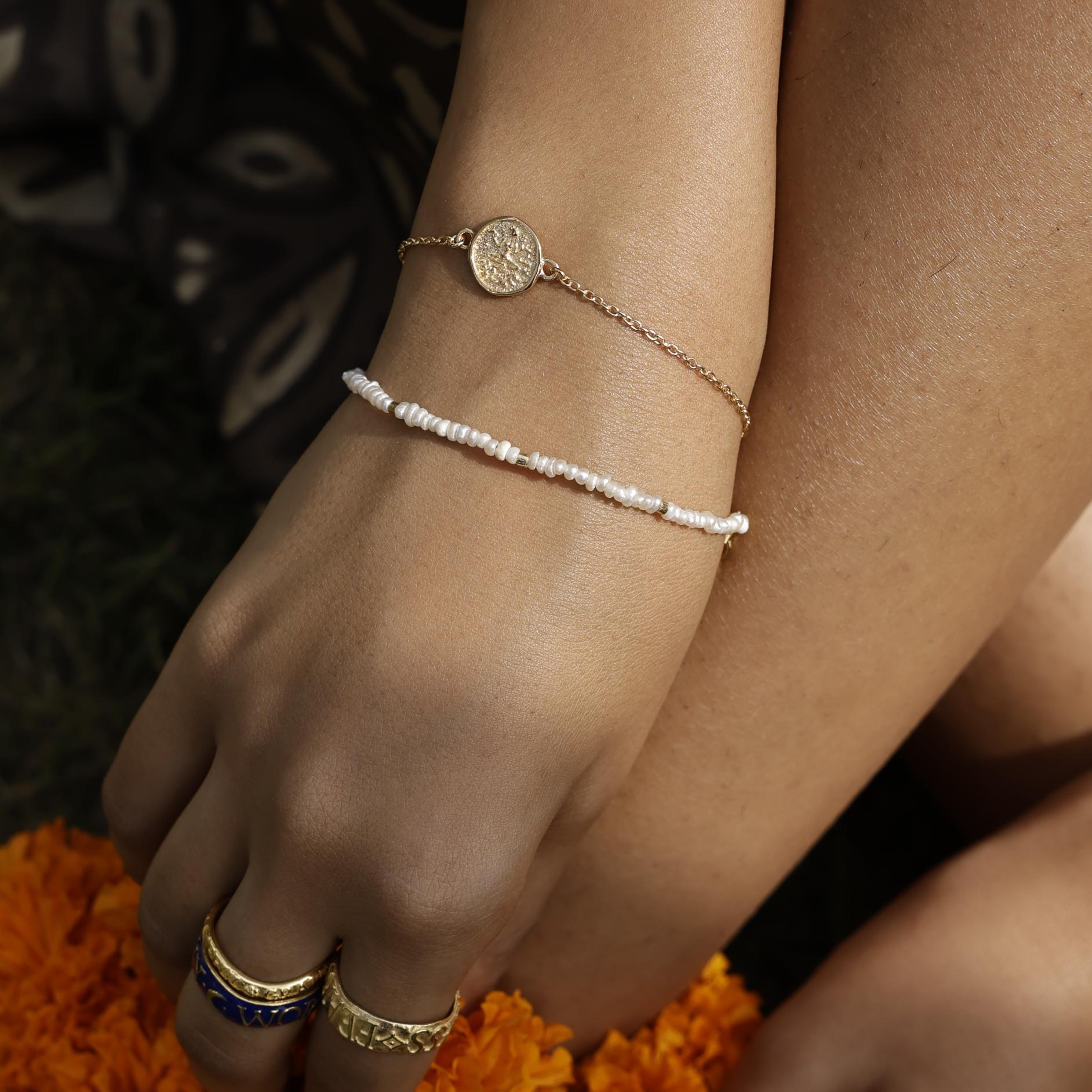 Close up of wrist wearing Baby Lakshmi stacking bracelet with delicate pearl bracelet by Loft & Daughter