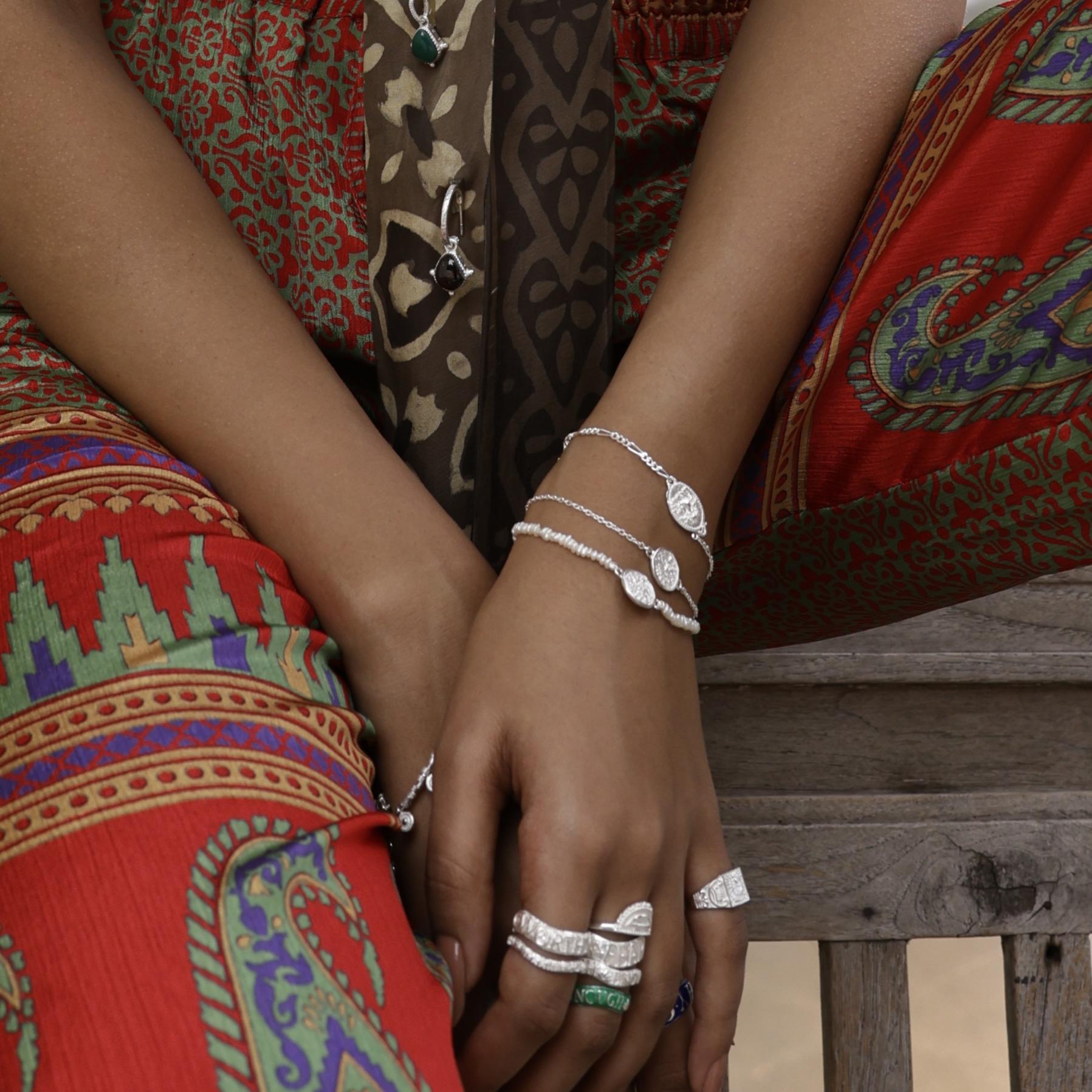Model wearing dainty boho stacking bracelets by Loft & Daughter featuring Lakshmi and Durga goddess coins worn with silver stacking rings