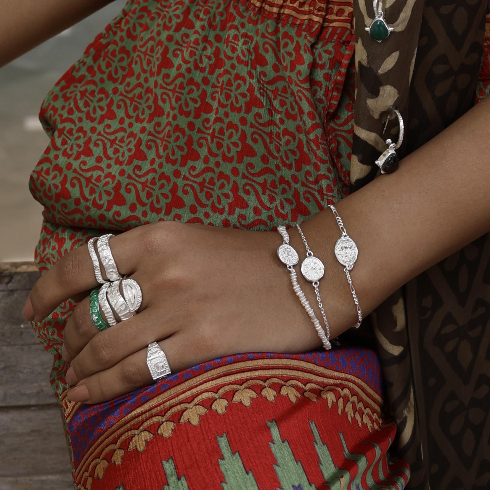 Dainty silver stacking bracelets by Loft & Daughter worn on model with multiple stacking rings with patterned trousers