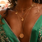 Close up of model wearing gold ganesh and divine compass pendants by Loft & daughter