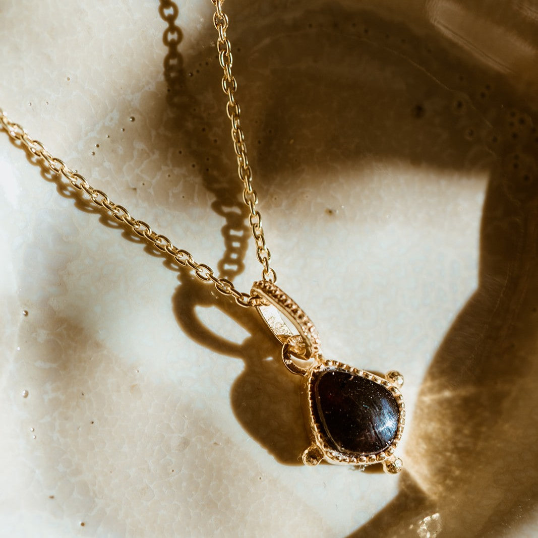 Gold and red garnet protective talisman pendant in sunlight