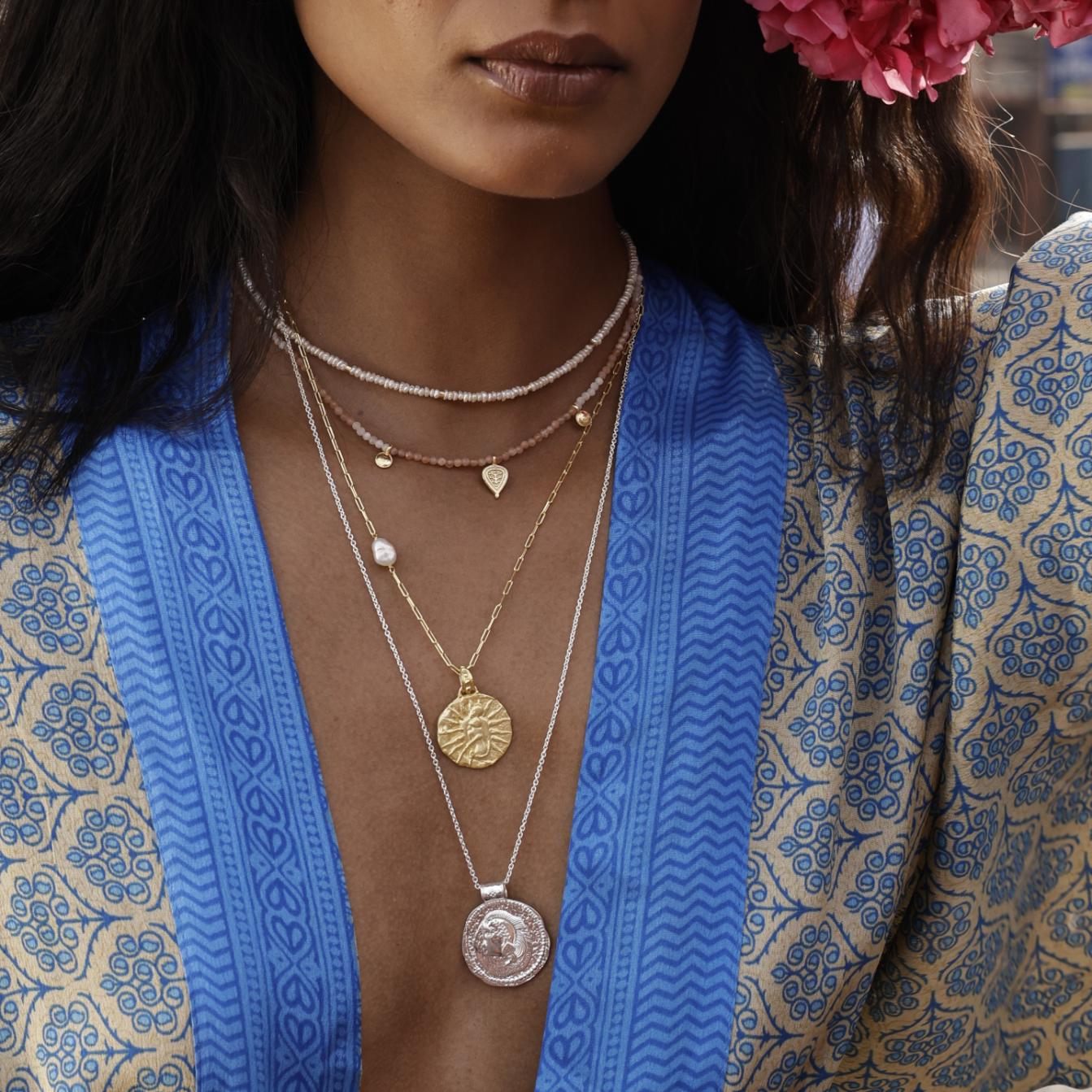 Woman wearing layered necklaces with a blue and patterned kimono