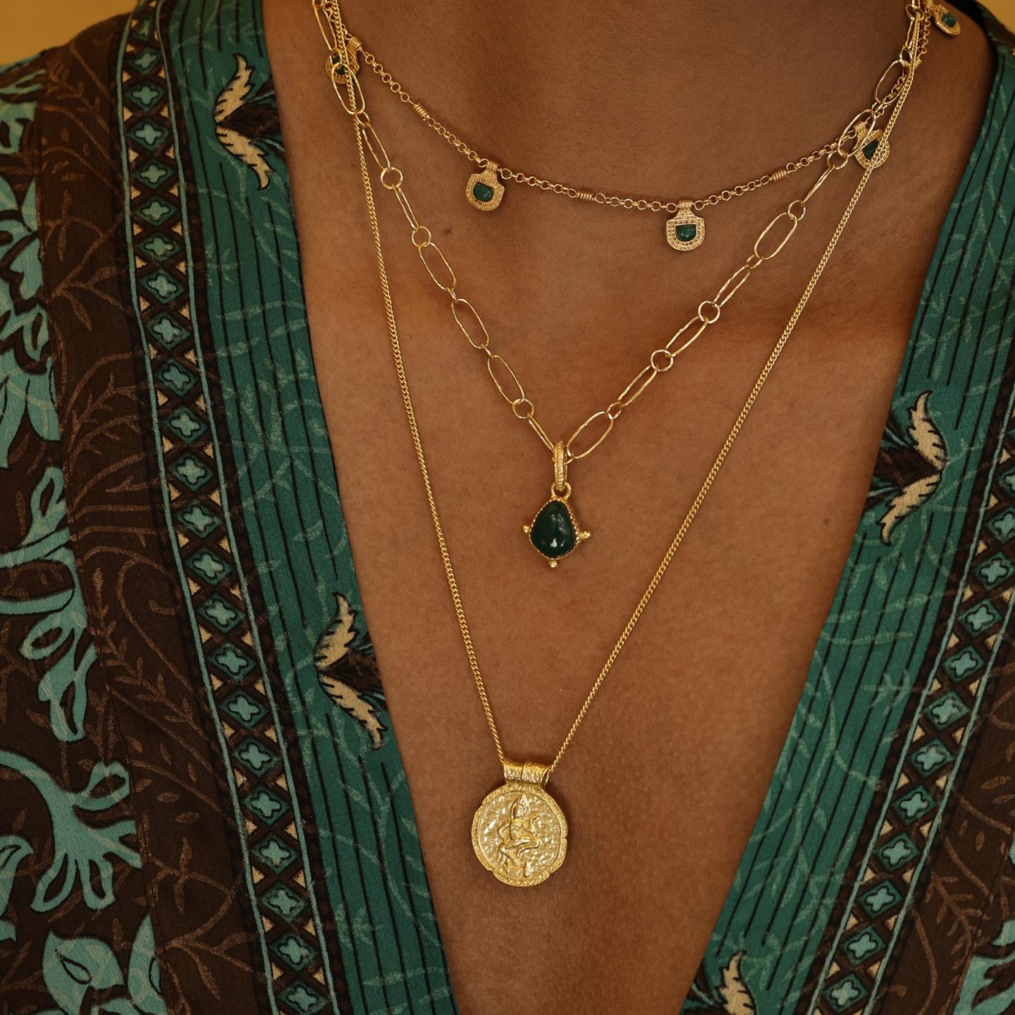 Close-up of model wearing Forever Young Pendant, capturing soft light on engraved Apsara design