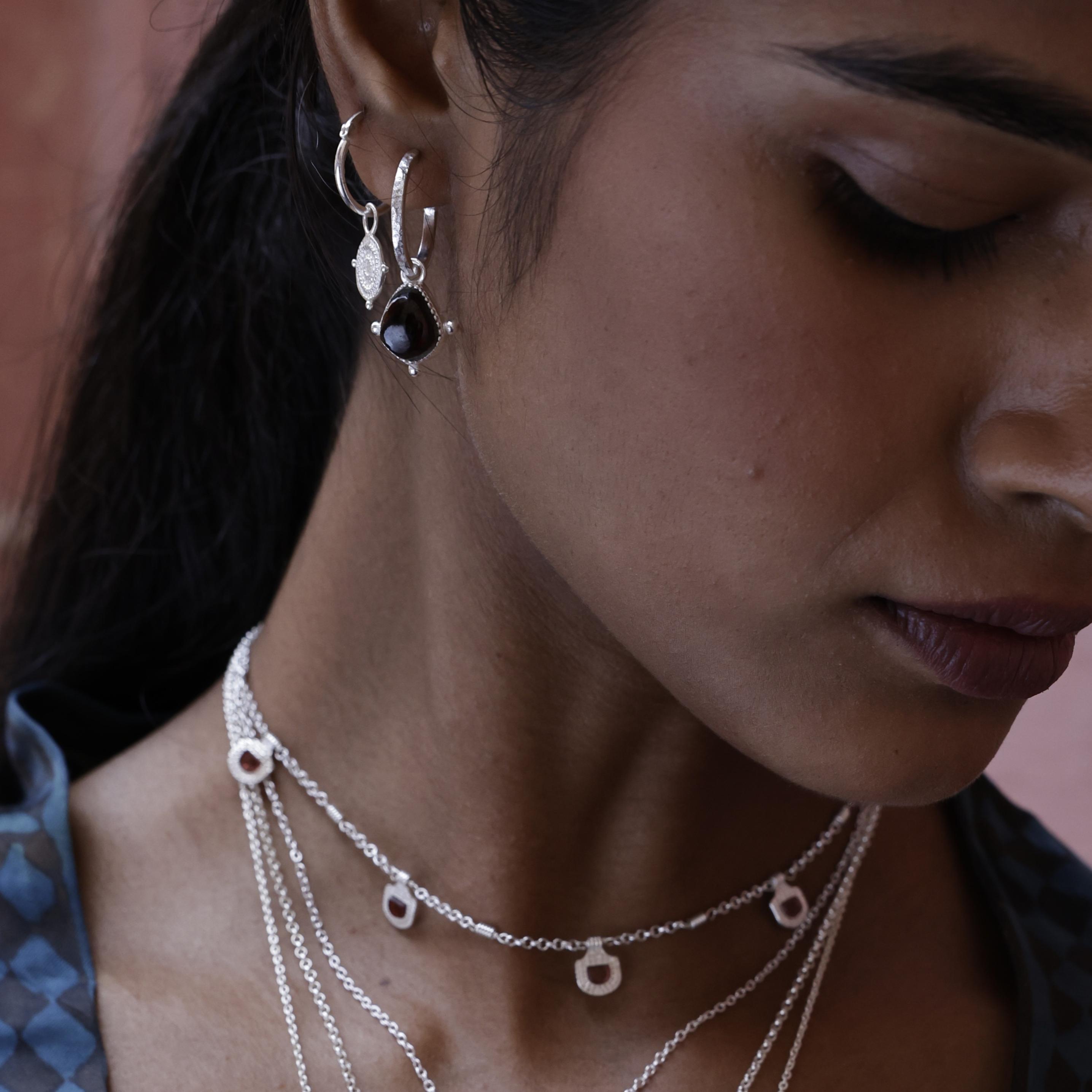 Close-up of a woman wearing silver boho earrings and necklaces.