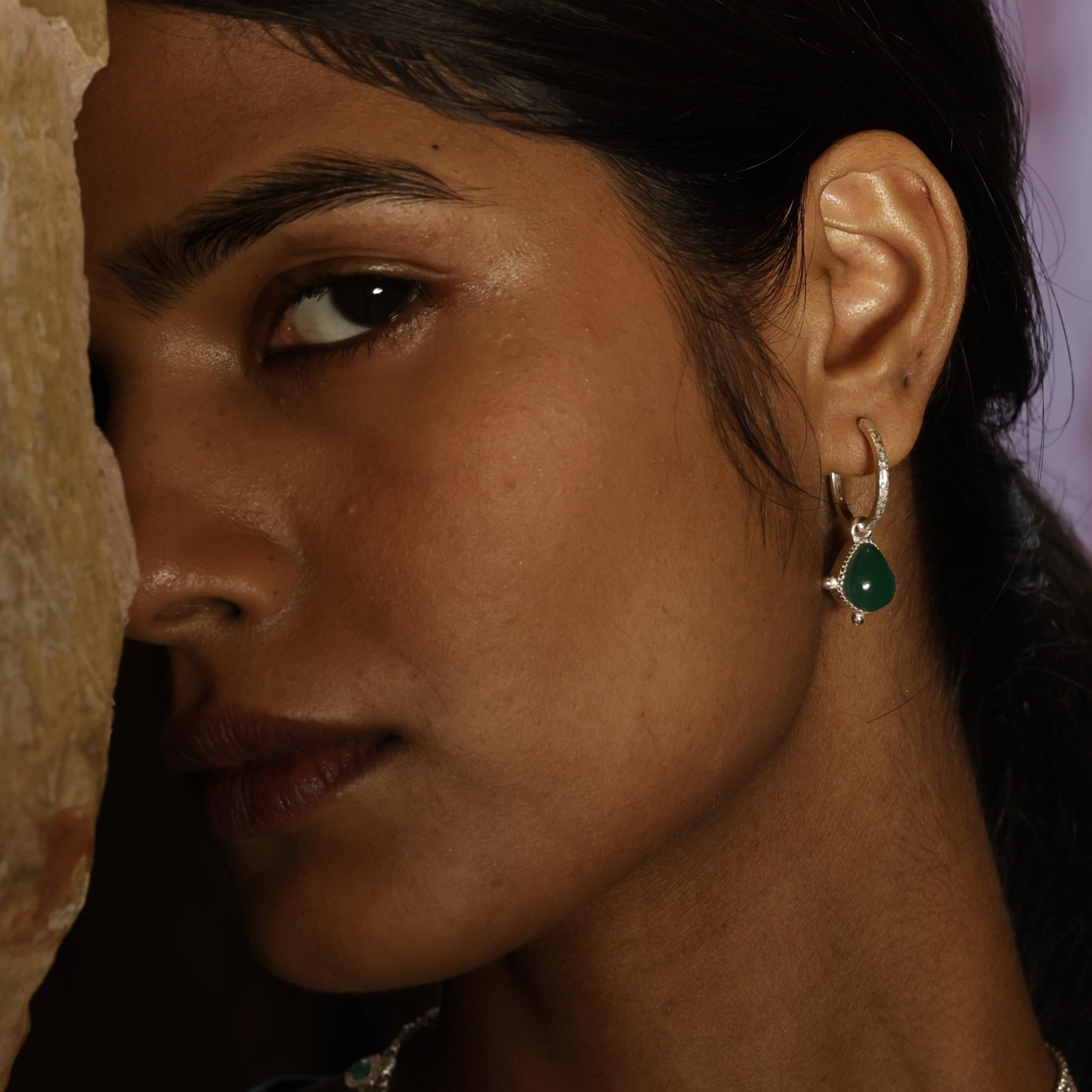 Close-up of a woman wearing a green gemstone earring.