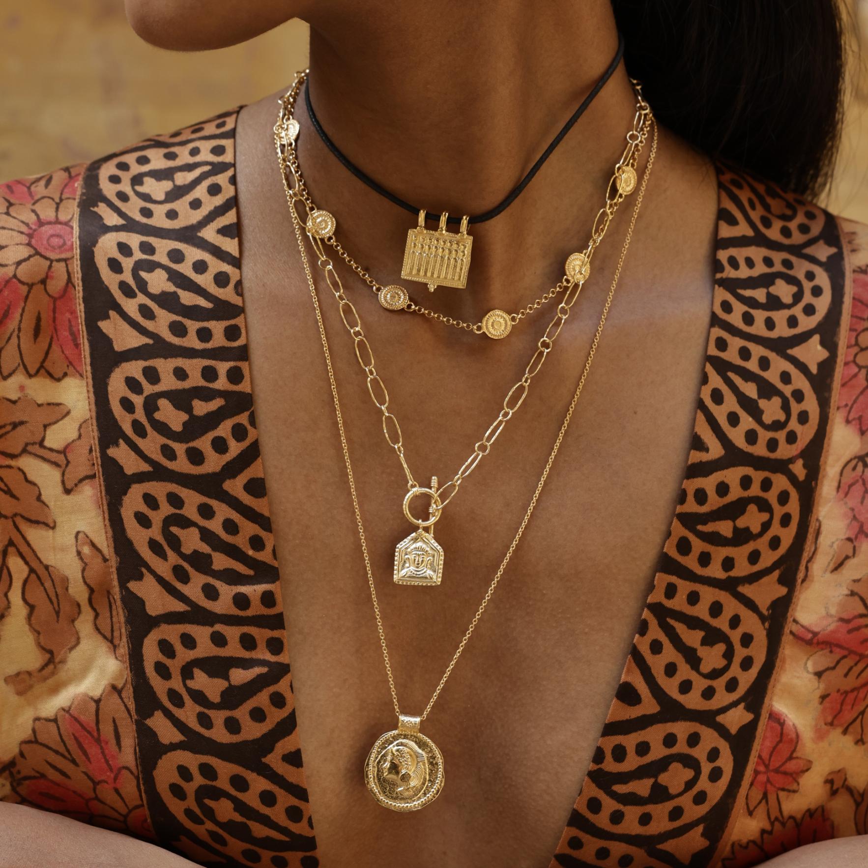 Athena gold pendant styled as a modern-day shield of inner strength worn with layering pendants