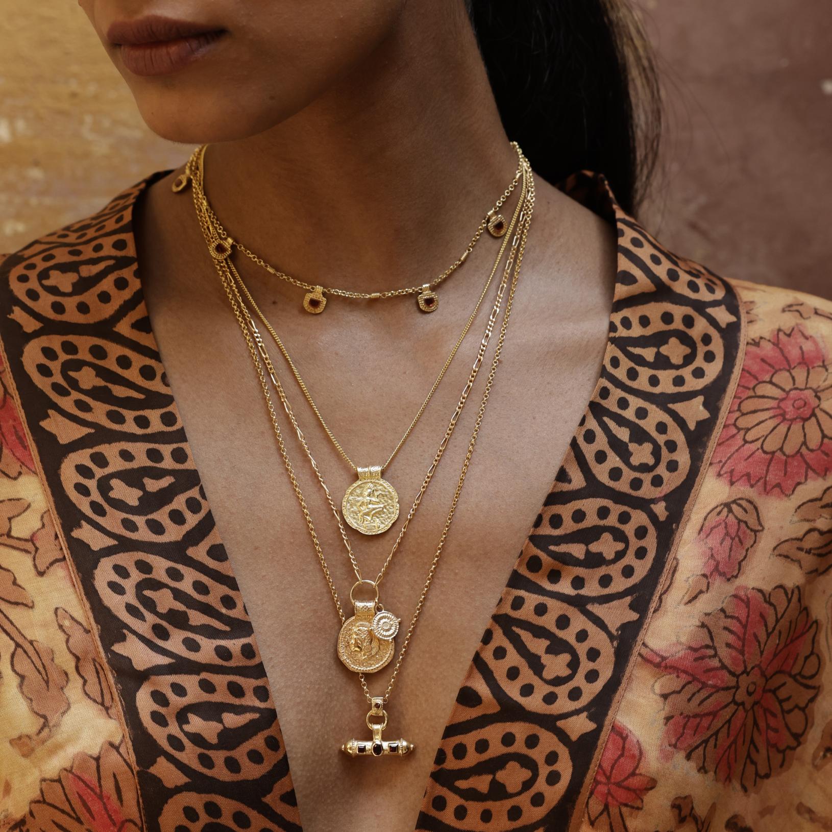 Model wearing the Nivara Amulet garnet necklace layered with other Loft & Daughter jewellery including You Got This and Forever Young pendants