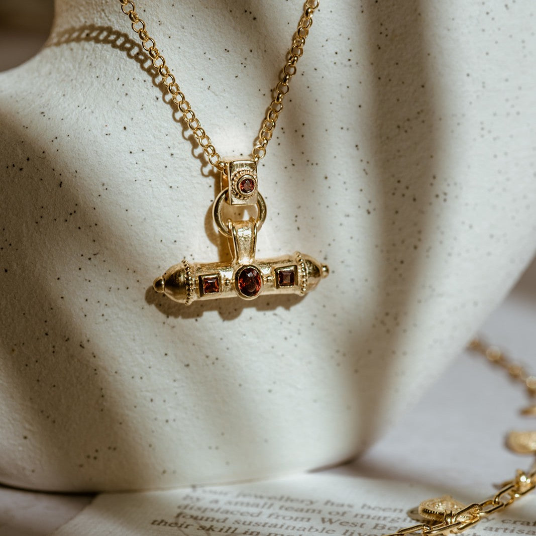 Handcrafted garnet amulet necklace photographed against natural stone background