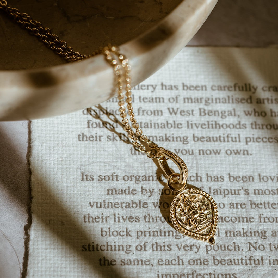 Delicate gold vermeil Ganesha pendant symbolising luck, wisdom, and fresh starts photographed in soft lighting 