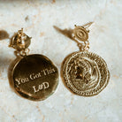 Gold earrings with 'You Got This' and initials on a marble surface