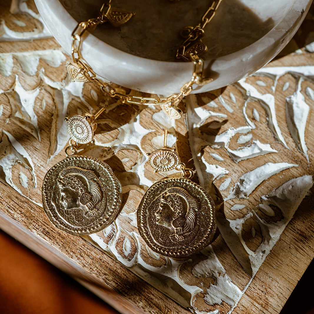 Large coin earrings featuring the goddess Athena on a decorative surface