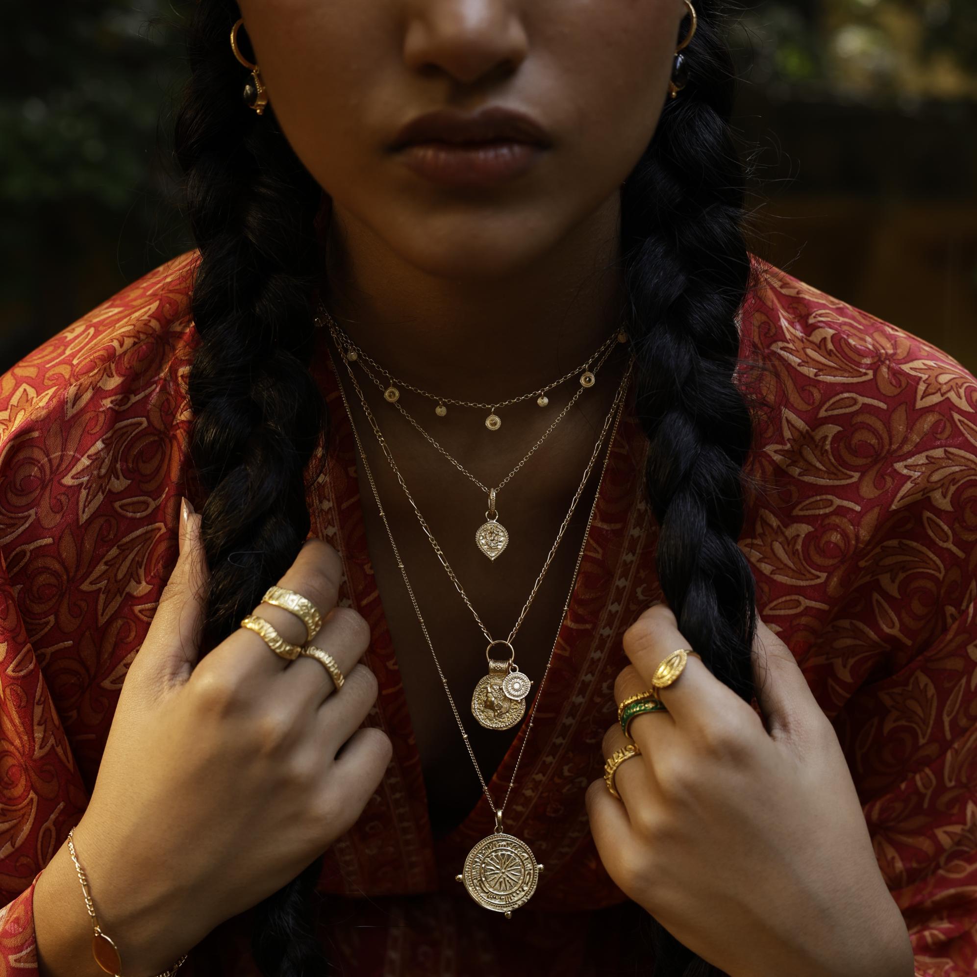 Model wearing Baby Ganesha pendant layered with other meaningful Loft & Daughter talismans worn with patterned kimono
