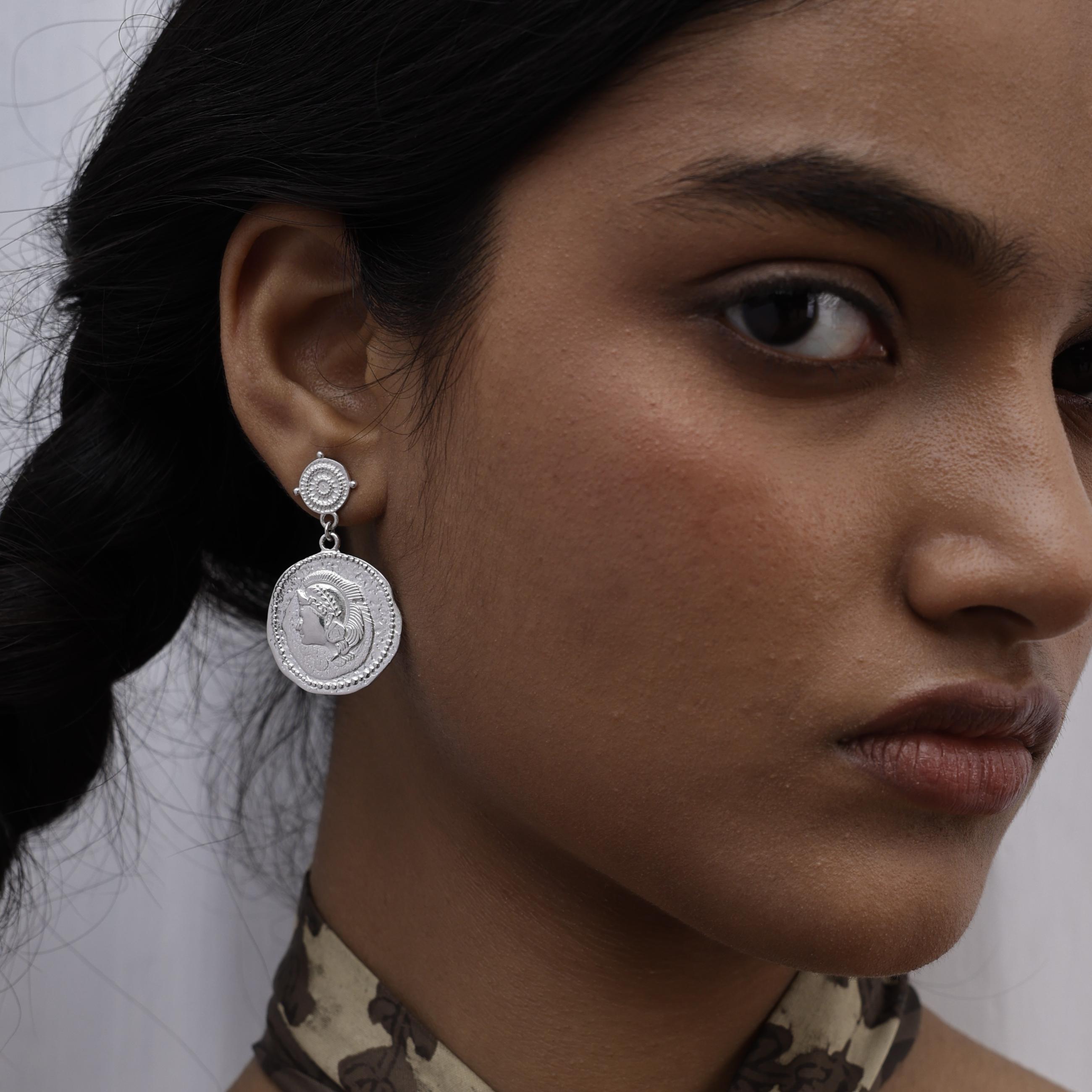 Close-up of a model wearing large silver coin Athena earrings by Loft & Daughter