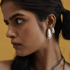 Close-up of a woman wearing tribal inspired  silver earrings with a yellow background