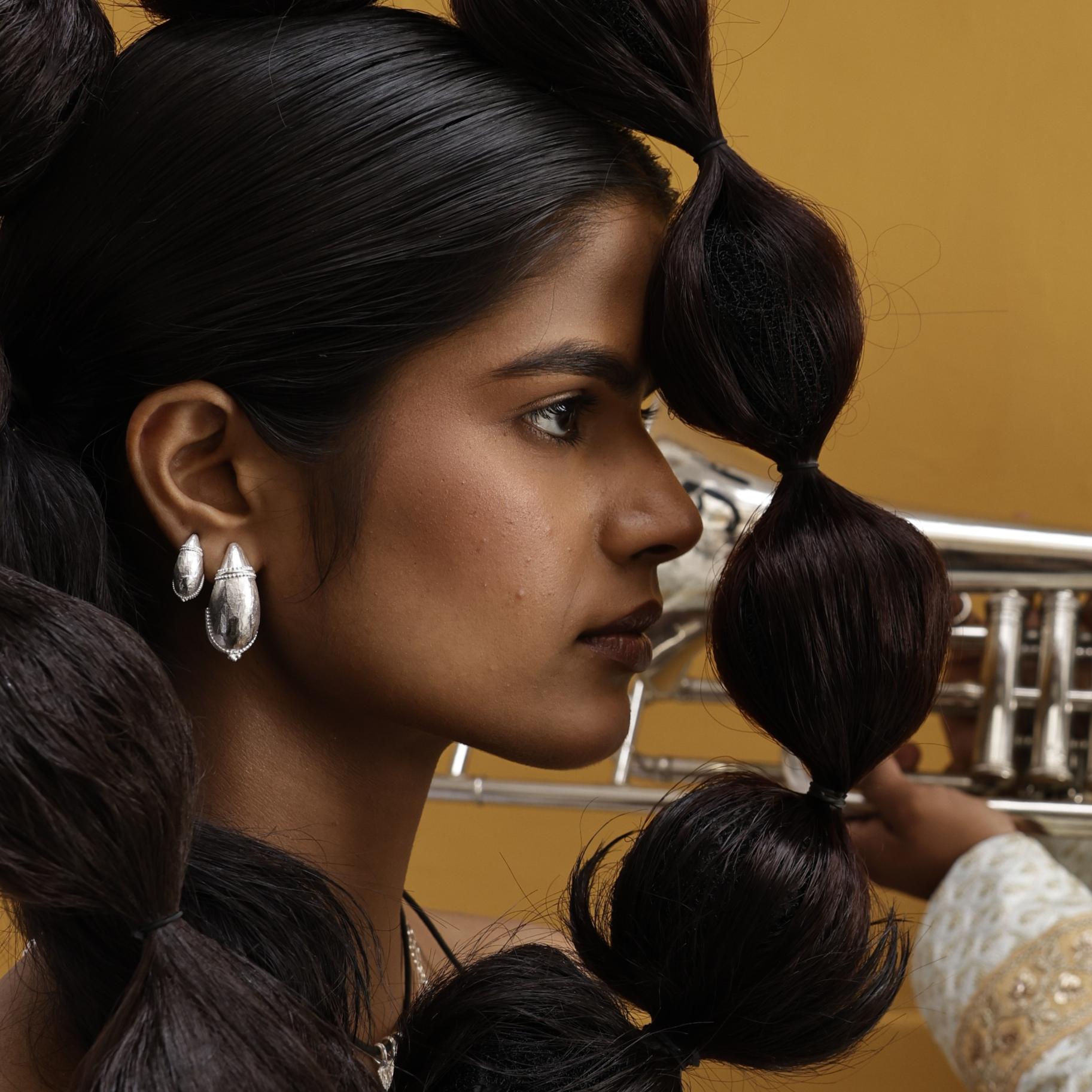 Woman with styled hair in braids wearing stacking silver dome hoop earrings in large and small