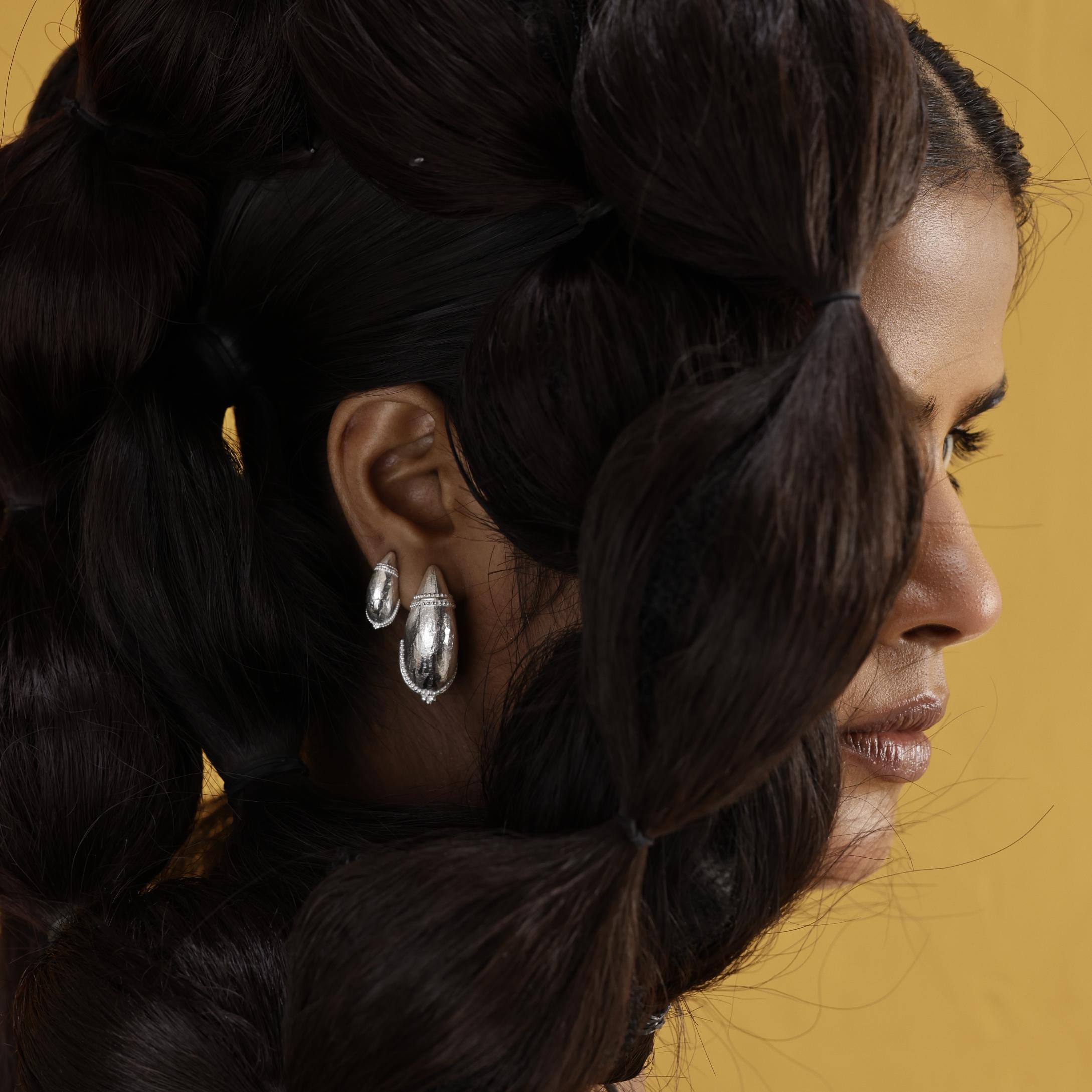 Close-up of a woman's profile with braided hair and domed tribal hoop earrings stacked