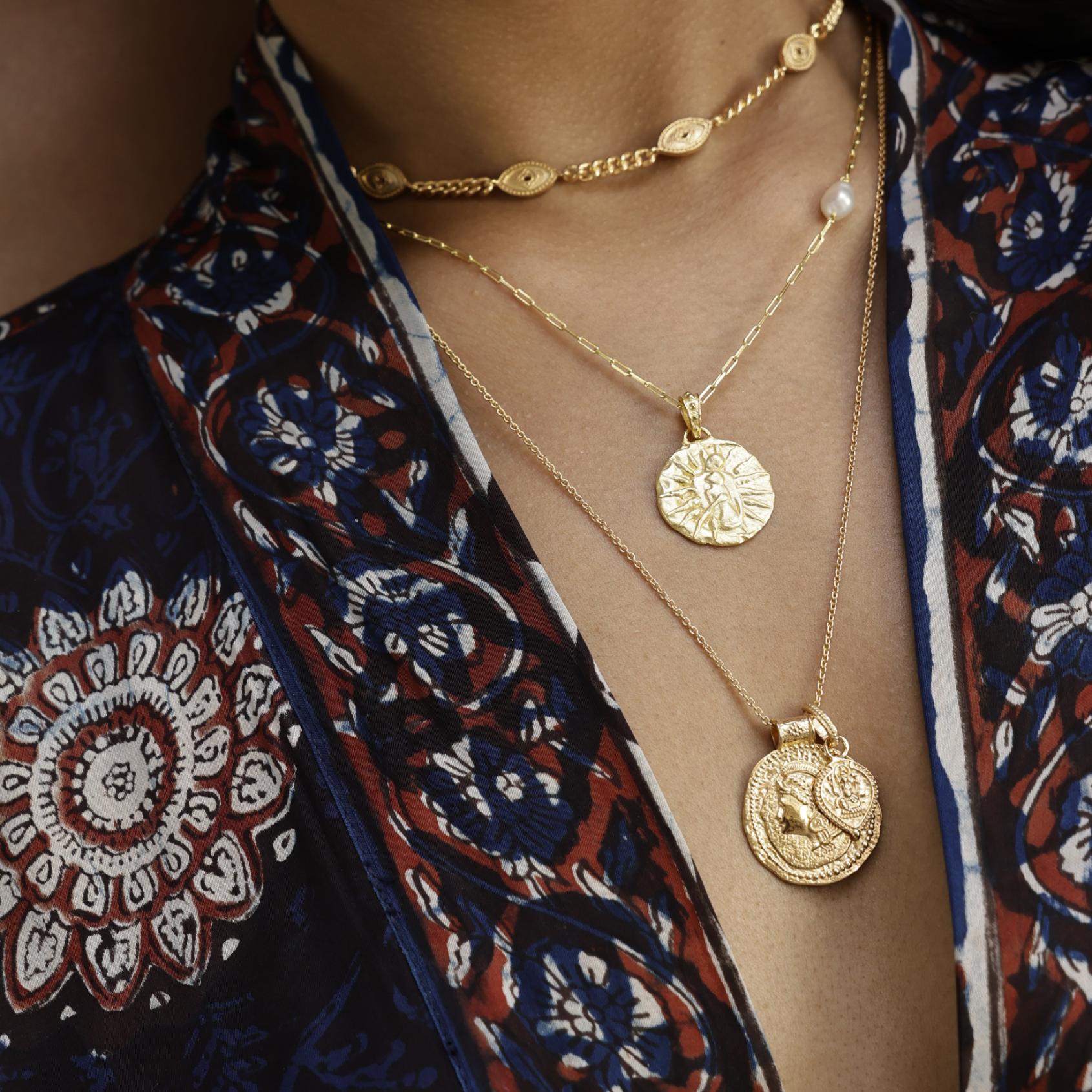 Gold necklaces with coin pendants featuring Athena and lord Ganesh on a model wearing a patterned kimono by Loft & Daughter