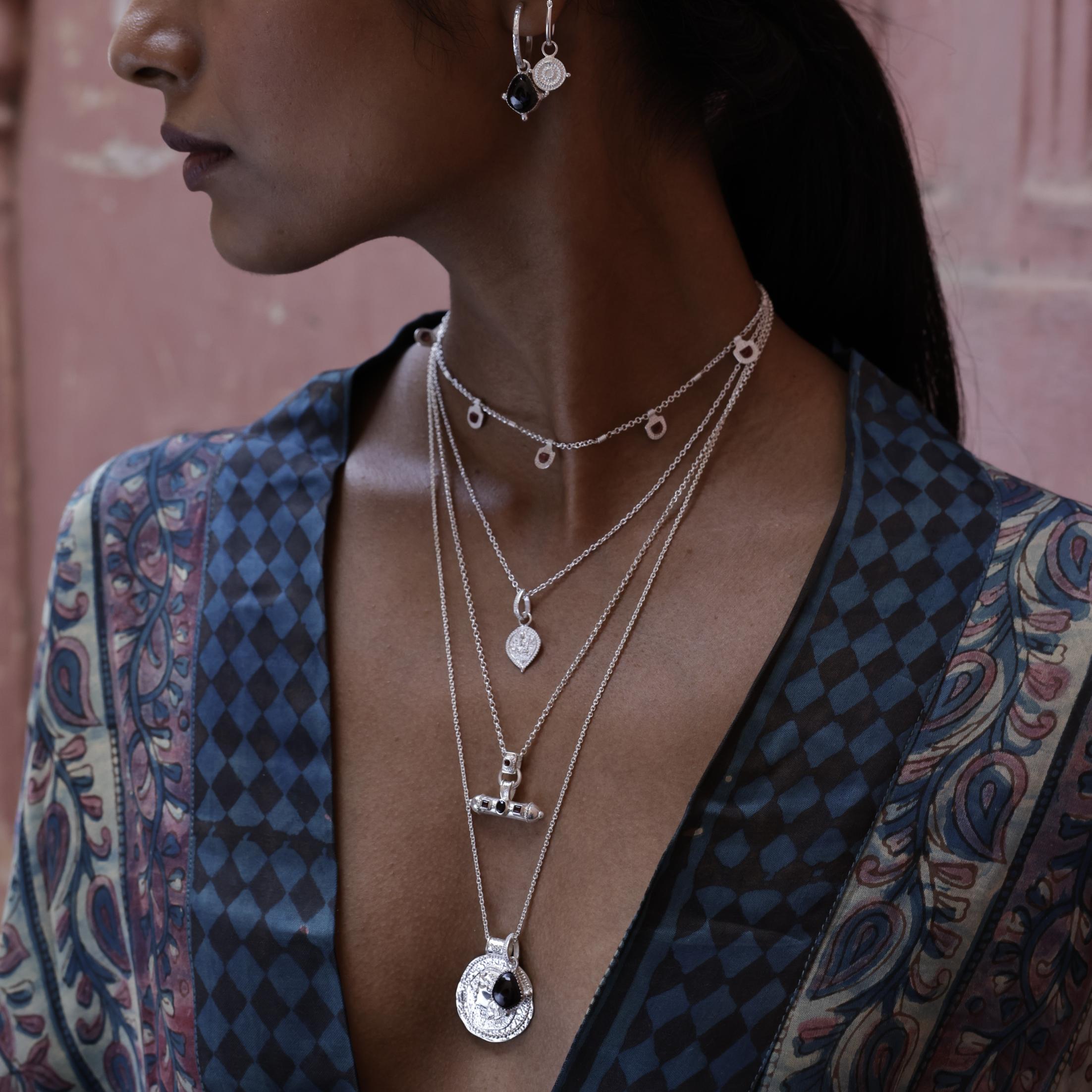 Model wearing Long Athena You Got This silver pendant layered with other meaningful talismans