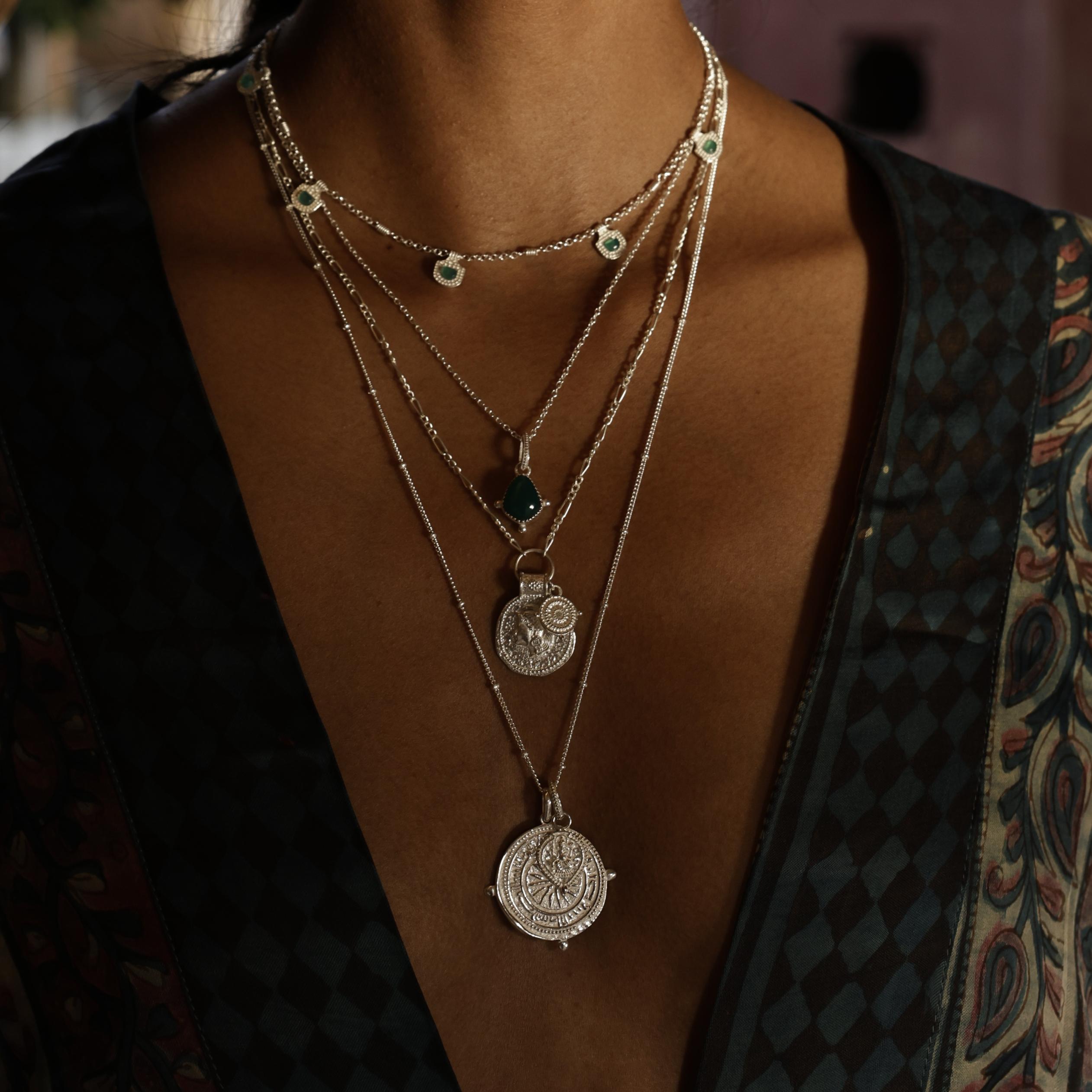 Boho silver layering pendants by Loft & Daughter on a model, featuring a Ganesh charm, green onyx pendant, Athena Coin Pendant and Long compass pendant