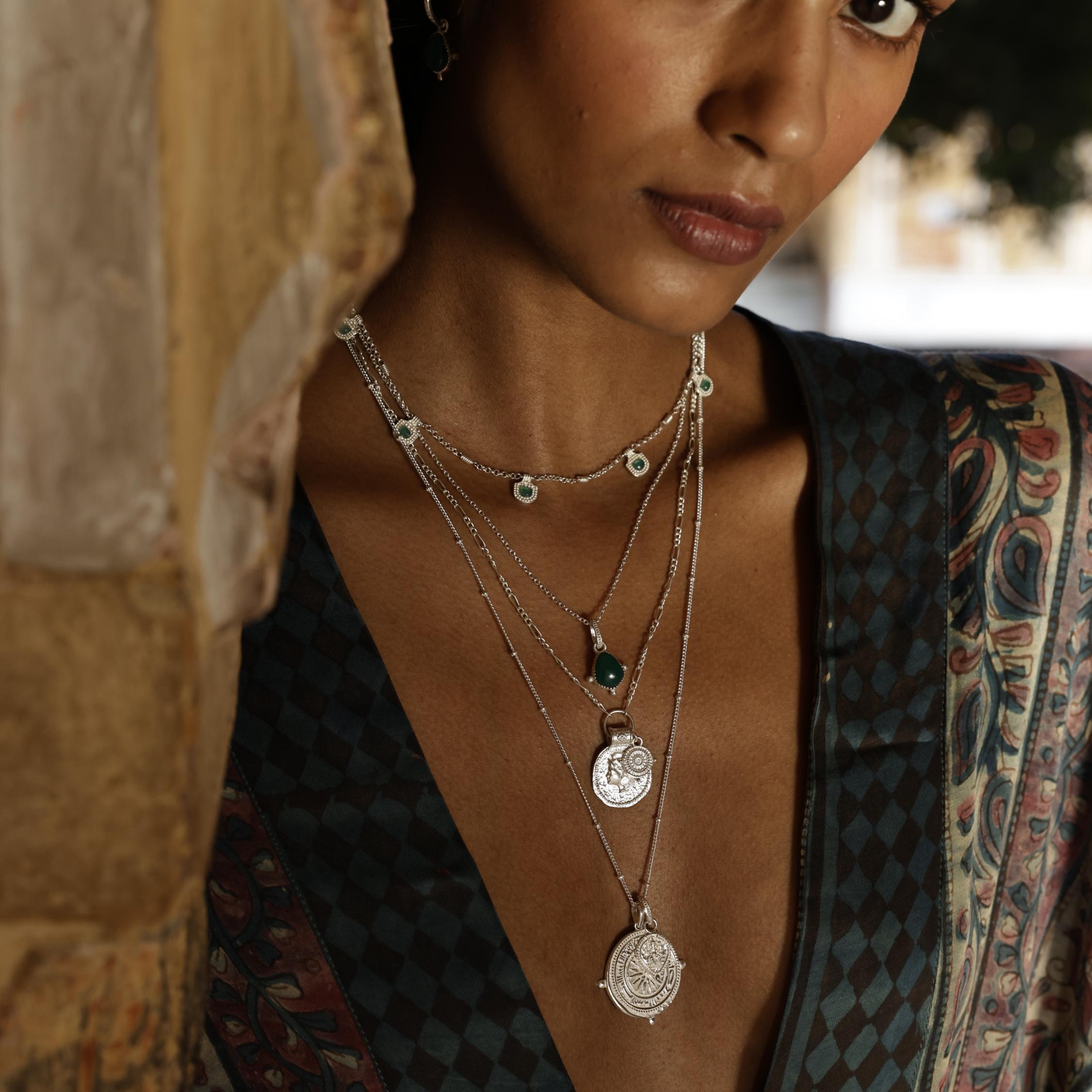 Woman wearing multiple Loft & Daughter silver necklaces with intricate designs for a bohemian layered necklace stack look