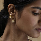 Model wearing Athena Shield Hoop Earrings, a subtle nod to the goddess of wisdom and courage