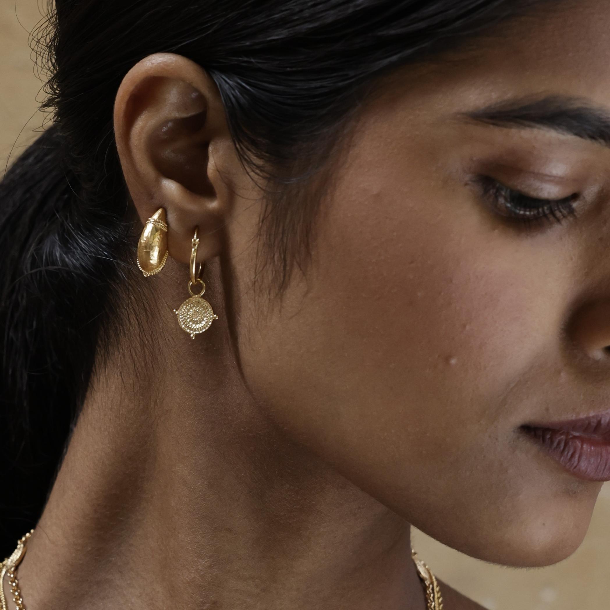 Model wearing Athena Shield Hoop Earrings, a subtle nod to the goddess of wisdom and courage