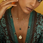 Woman wearing the Forever Young Pendant layered with other gold talismans, symbol of confidence and timeless femininity