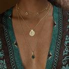 Gold necklaces with green pendants on a person wearing a patterned kimono