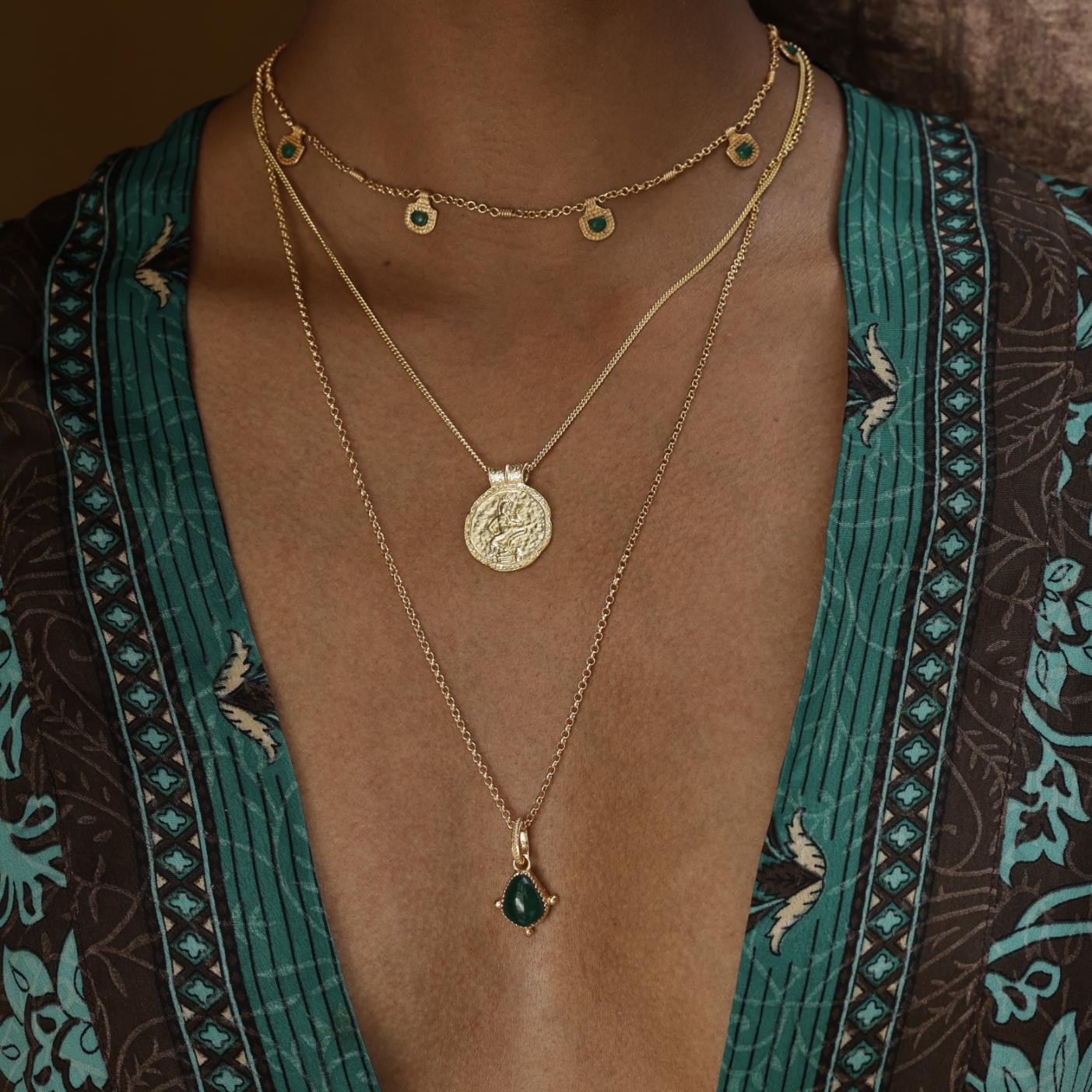 Gold necklaces with green pendants on a person wearing a patterned kimono