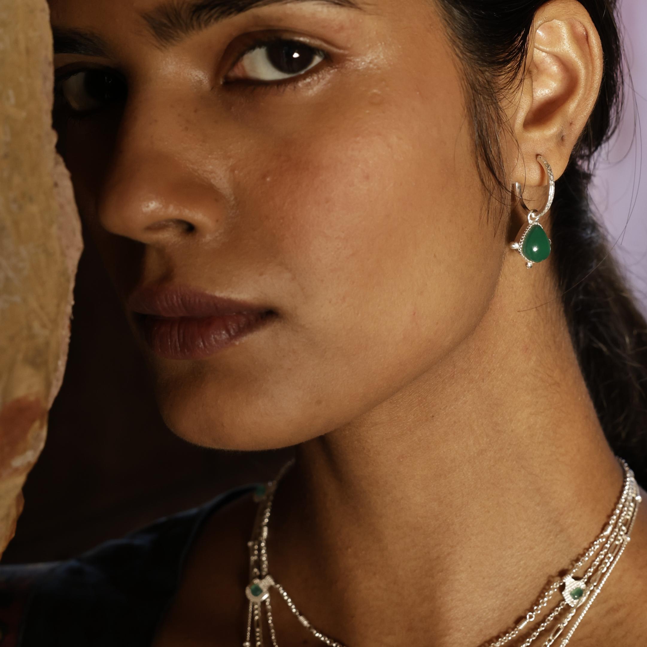 Close-up of a woman wearing a silver earring with a green gemstone.