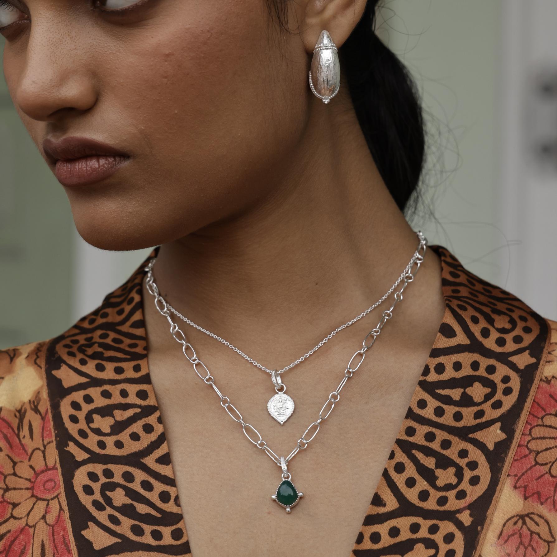 Woman wearing a silver necklace with a garnet gemstone, earrings, and a patterned kimono