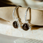 Silver hoops with garnet gemstone on marble background