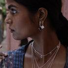 Woman wearing small silver shield hoop earrings layered with other Loft & Daughter talismans