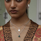 Woman wearing a silver necklace with a garnet pendant, close-up of her neck and upper chest.