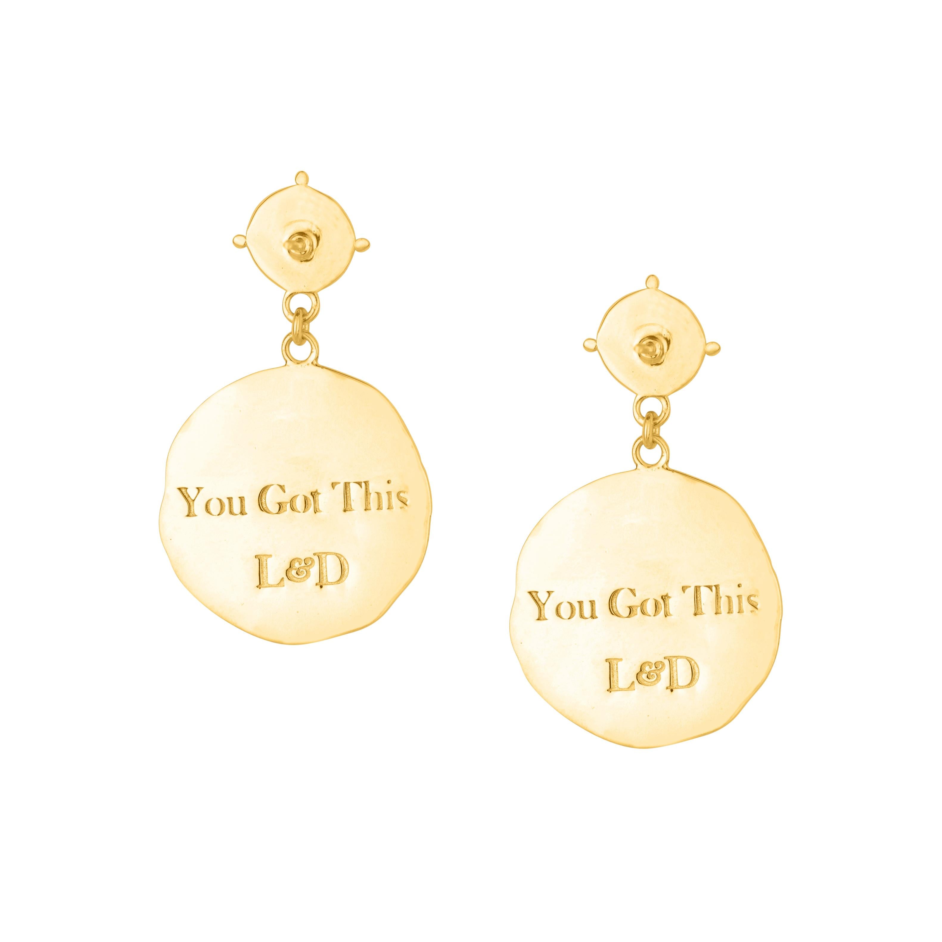 Gold earrings with 'You Got This L&D' text on a white background