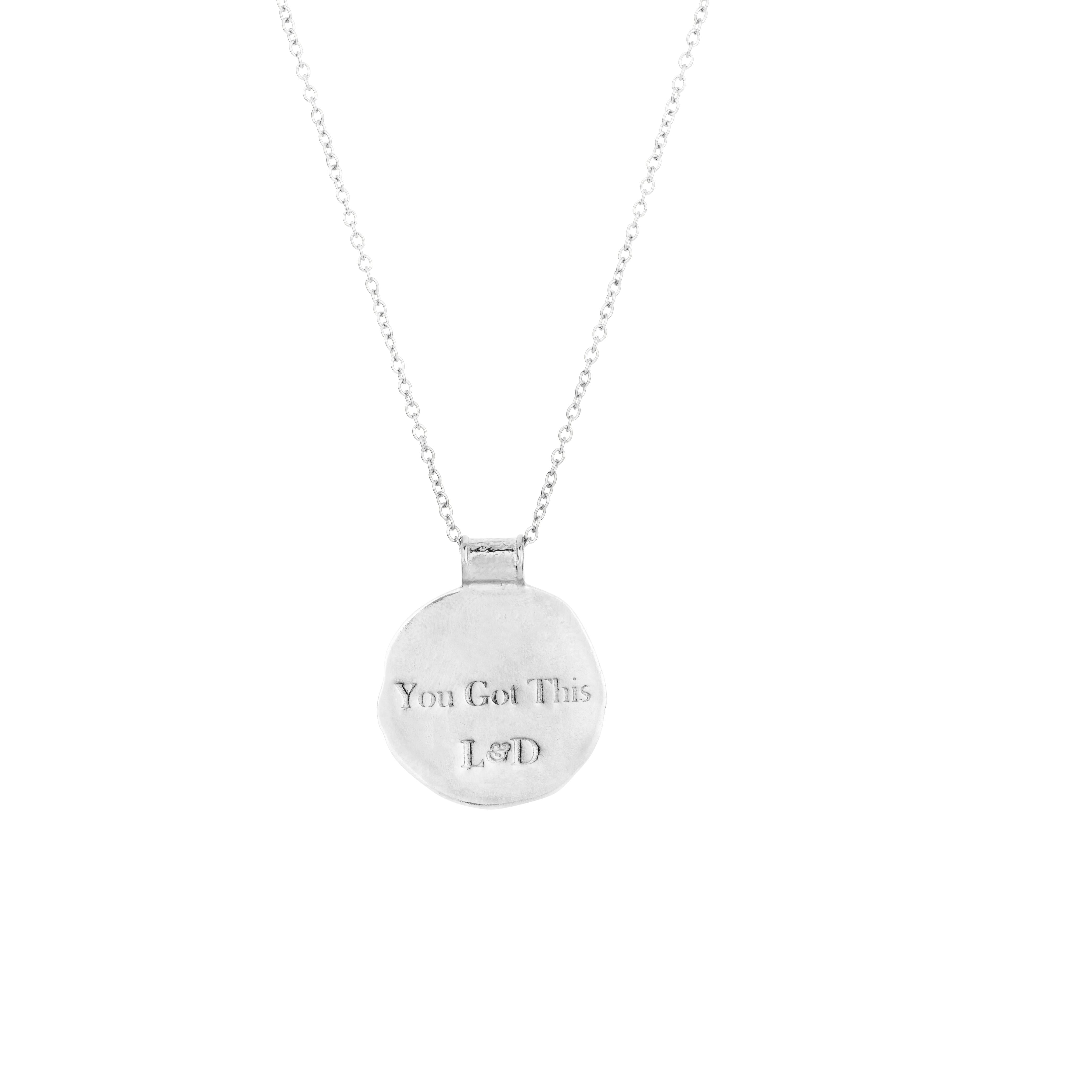 Silver coin pendant with You Got This engraved on the back on a white back ground by Loft & Daughter