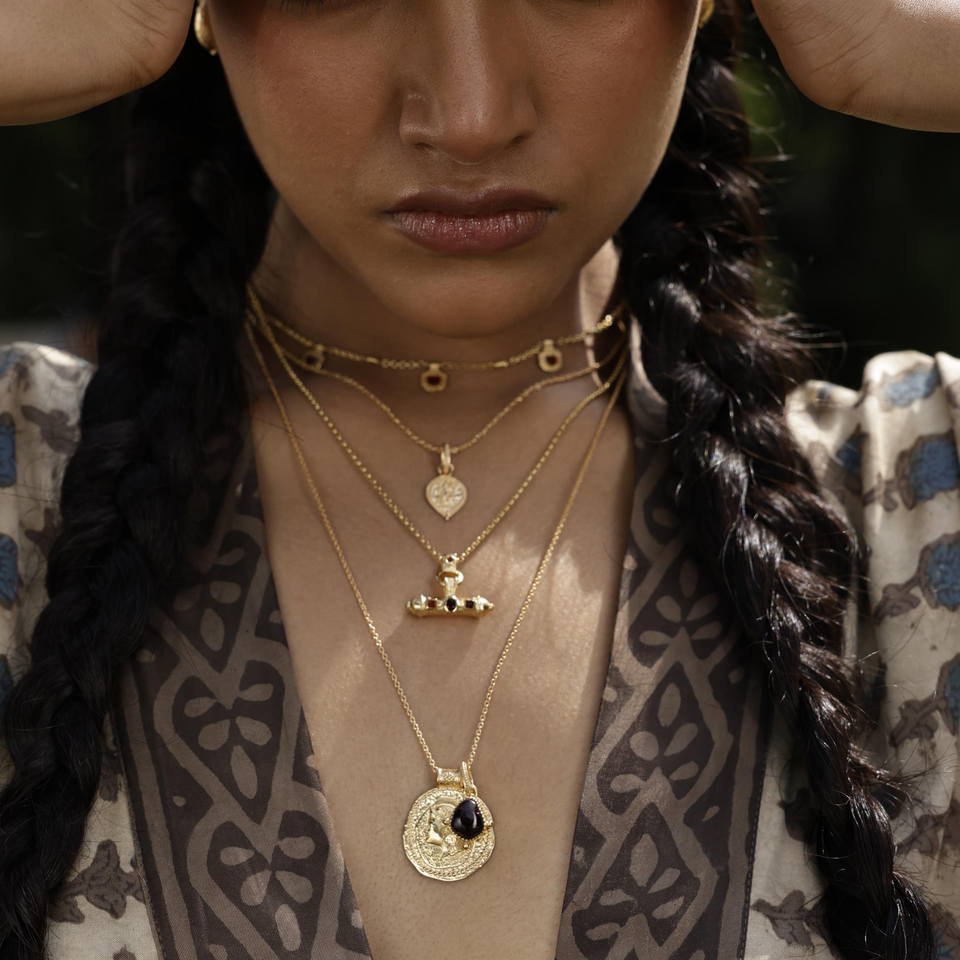Close-up of a person wearing gold Loft & Daughter boho necklaces with intricate designs.
