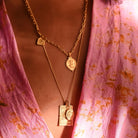 Gold ganesh and rectangle layering pendants on model wearing pink kimono