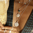 Close-up of layered Loft & Daughter with pendants featuring Ganesh, Athena & compass, on a model wearing a patterned kimono.