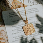 Gold Saraswati pendant necklace draped across a jewellery care card