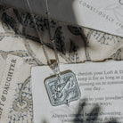 Silver Saraswati pendant necklace on a jewellery care card with woven fabric background