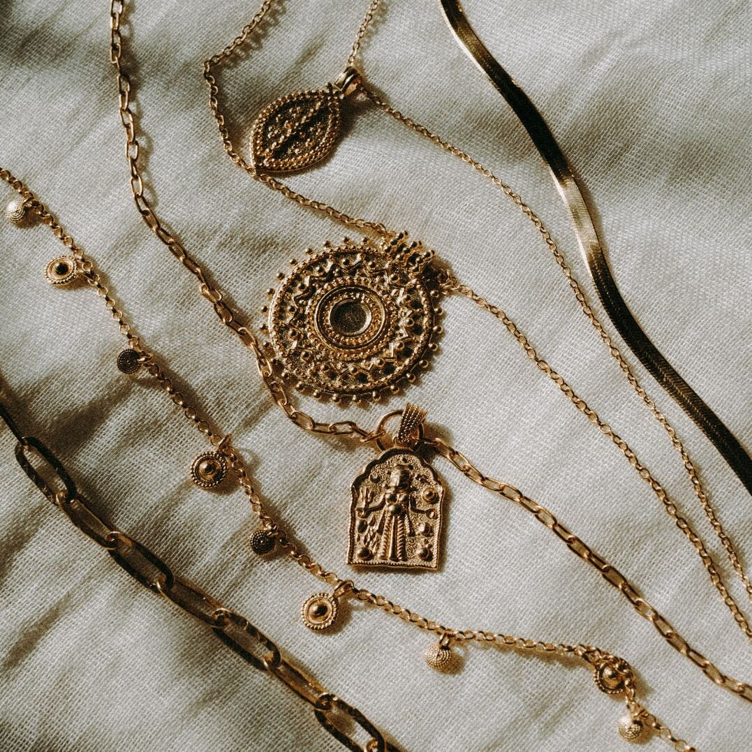 Gold vermeil gold boho stacking necklaces still life on beige fabric