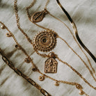 Gold vermeil gold boho stacking necklaces still life on beige fabric